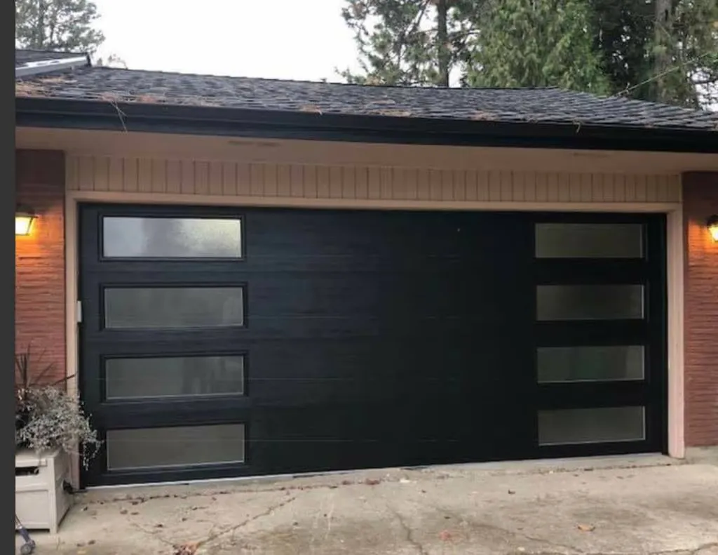 Modern black garage door with glass panels enhancing a home exterior