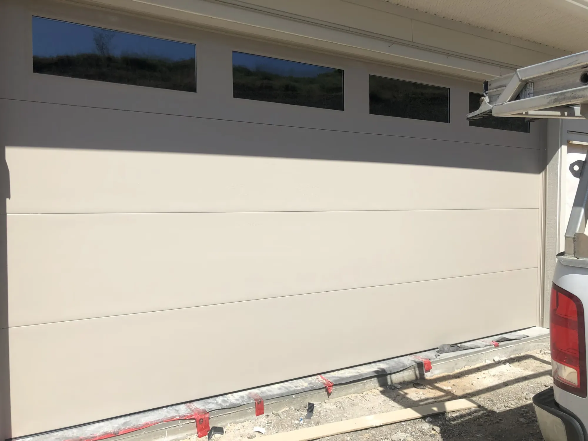 Flush sandstone garage door with a row of glass windows