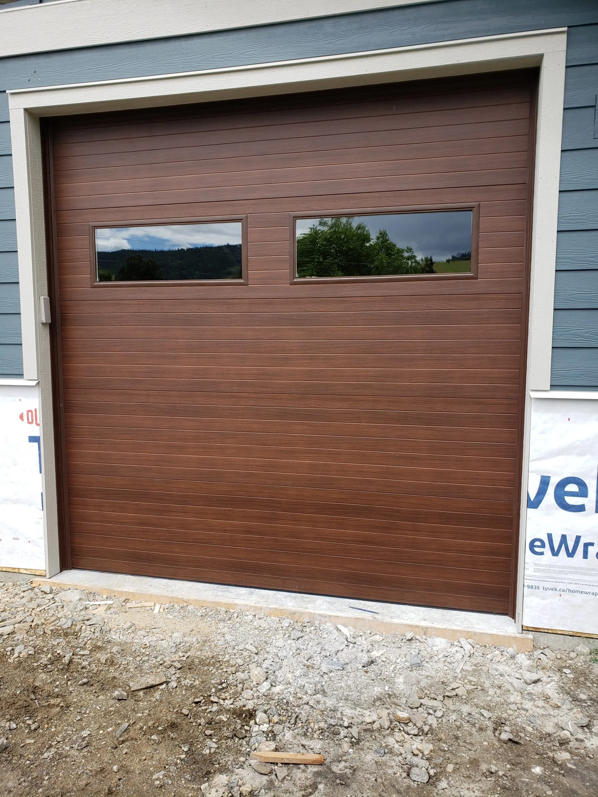 Contemporary flush garage door in walnut woodgrain on a modern home